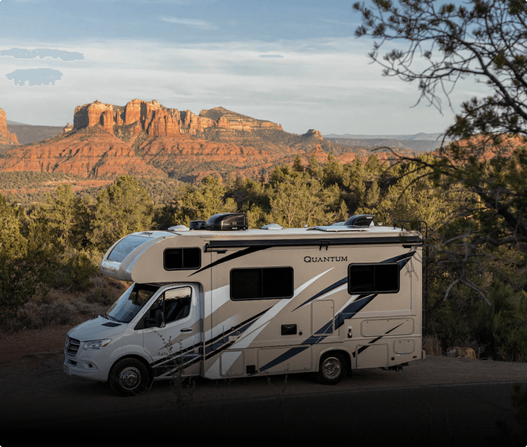 Class C motorhome parked below red rock cliffs